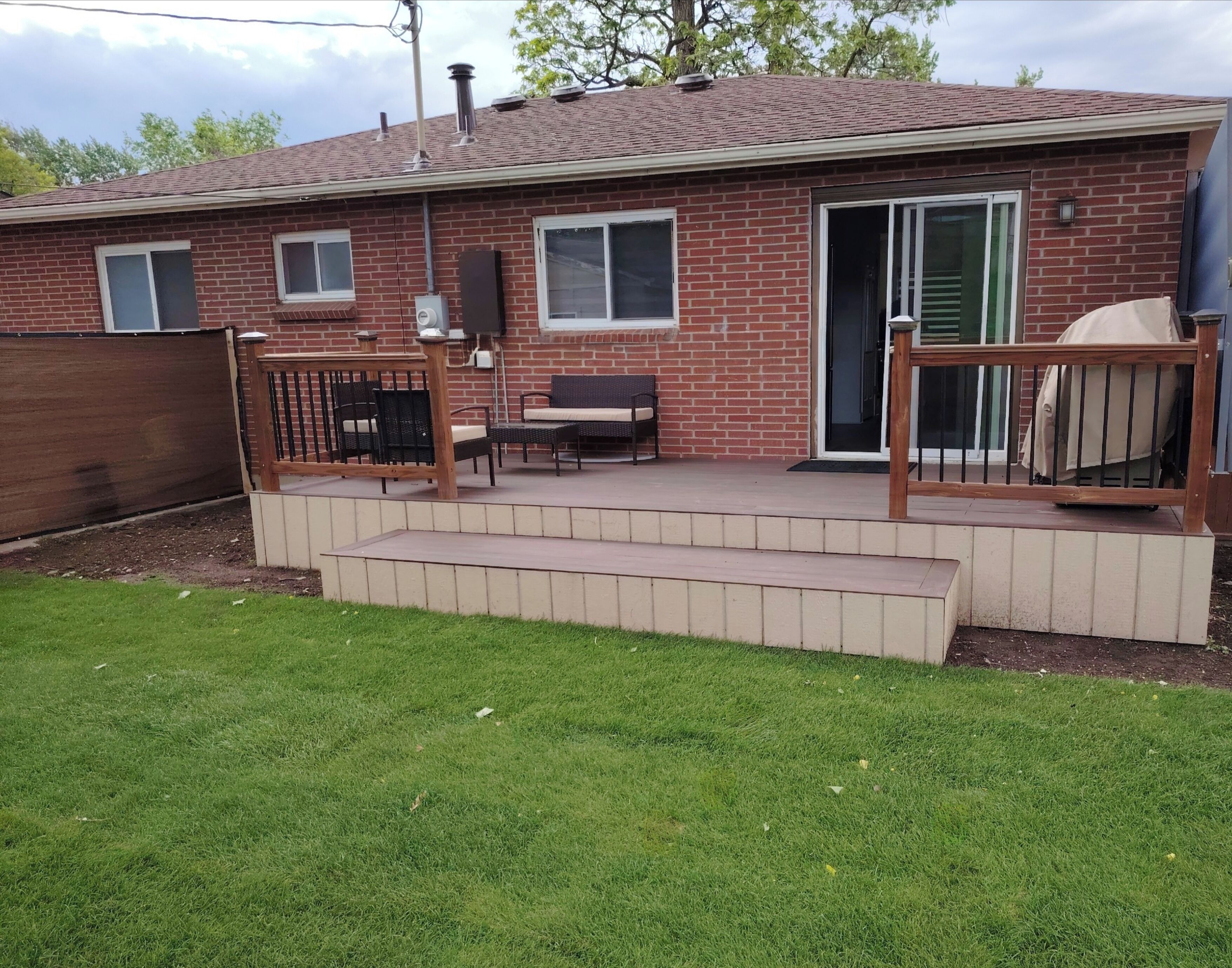 A brick house with a patio area featuring outdoor furniture, a sliding glass door, and a covered grill.