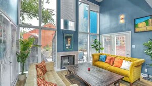 A modern living room with a yellow sofa, a fireplace, and large windows. - D Houston Oasis Private Jacuzzi Loft 65ft Pool (Houston)