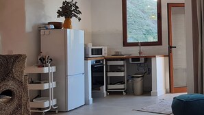 Eine kompakte Küche mit Kühlschrank, Mikrowelle und Backofen. Ein kleines Waschbecken und ein Fenster mit Blick auf Grünflächen vorhanden.