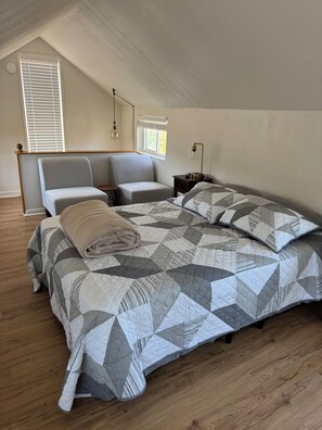 Une chambre à coucher avec un lit, deux chaises, une table de chevet et une fenêtre avec des stores.