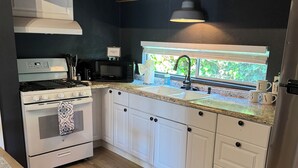 Eine moderne Küche mit weißen Schränken, einem Edelstahlkühlschrank, einem eingebauten Backofen und einer Mikrowelle.