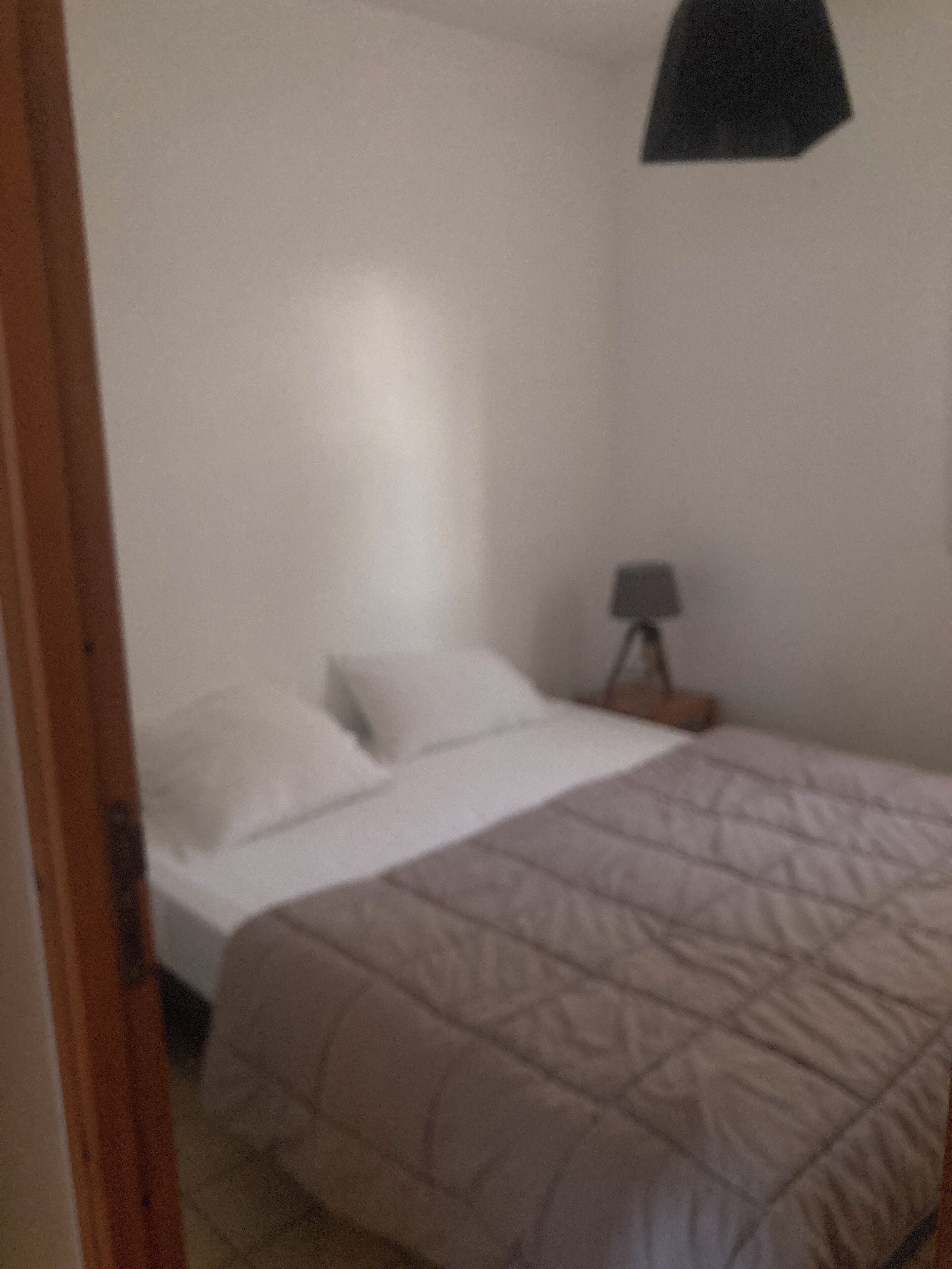 A bedroom with a bed, a bedside table, and a lamp.
