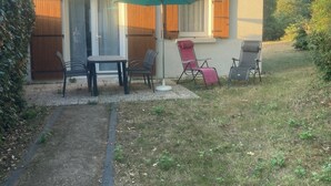 A house with a patio area featuring a table and four chairs, a green umbrella, and a small garden. - Bright vacation home in the dunes, kerhillio beach (Erdeven)