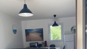 A compact living space with a sofa, a dining table with chairs, a kitchenette, and a large window. - Bright vacation home in the dunes, kerhillio beach (Erdeven)