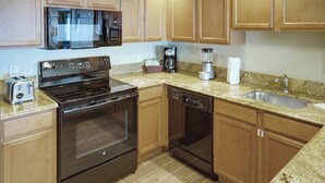 A kitchen with wooden cabinets, a stainless steel stove, a microwave, a coffee maker, and a dishwasher.