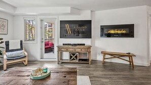 A modern living room with a fireplace, a mounted TV, and a comfortable seating area. - La Bohème | Pool Views | Hot Tub | Lake Access (Invermere)