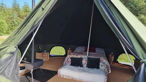 Ein Zelt mit einem Bett, einem kleinen Tisch und einem Stuhl.