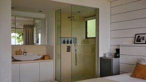 Een moderne badkamer met een douchecabine van glas, een groot wastafelmeubel en een spiegel.