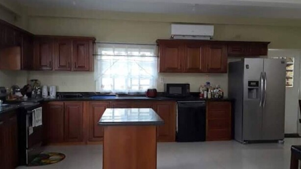 A kitchen with wooden cabinets, a central island, a refrigerator, and a microwave. - Luxurious Sea View From The Pool (Gulf View)