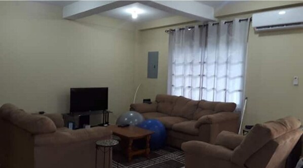 A living room with beige sofas, a television, exercise balls, and a window with curtains. - Luxurious Sea View From The Pool (Gulf View)