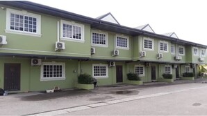 A row of green buildings with multiple windows and air conditioning units. - Luxurious Sea View From The Pool (Gulf View)
