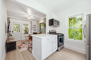 A modern kitchen with white cabinetry, a built-in microwave, a stove, and a refrigerator.