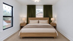 A bedroom with a single bed, two bedside tables, a ceiling fan, and a window with curtains.
