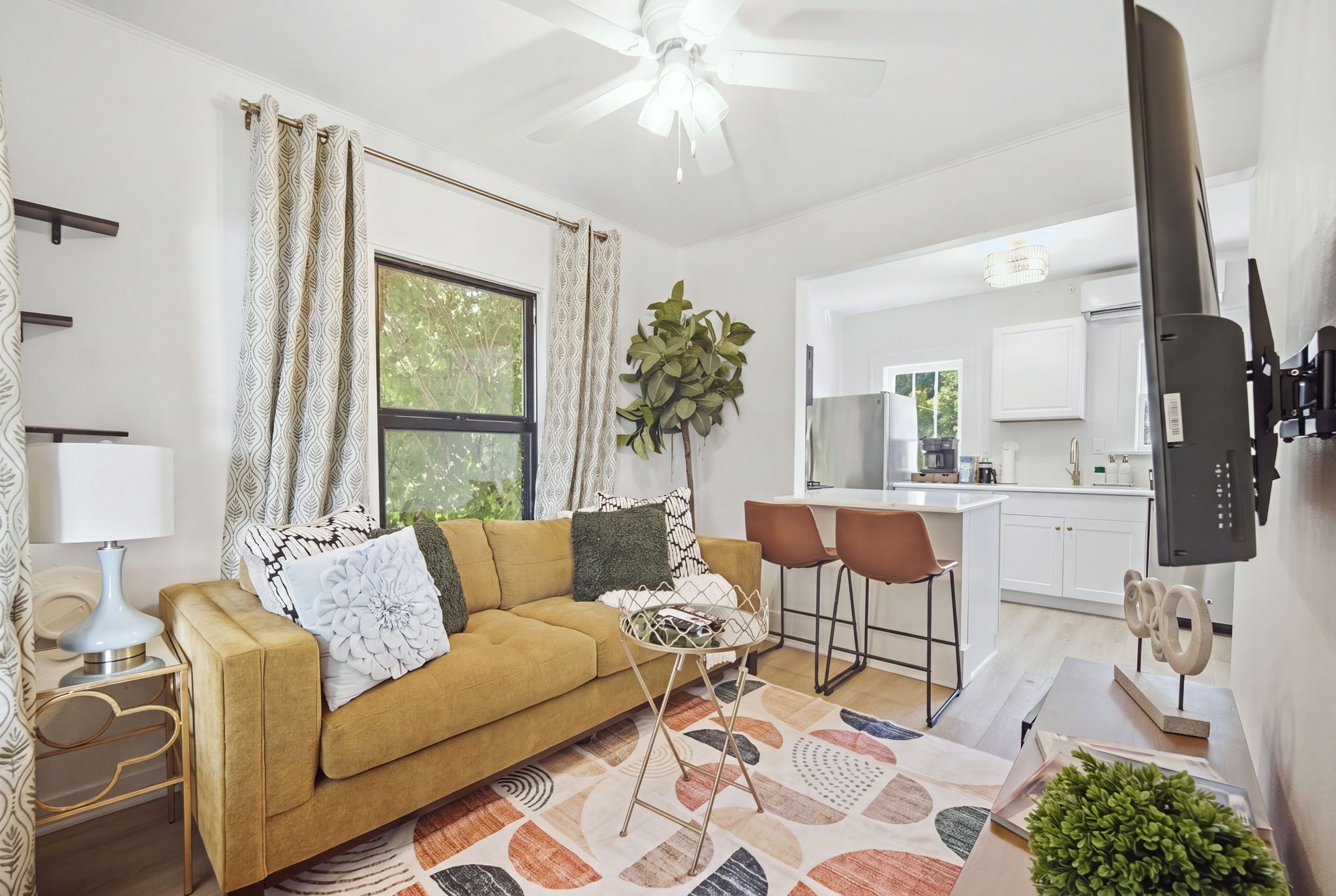 A living room with a sofa, a coffee table, and a TV mounted on the wall.