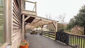 Eine Holzterrasse mit einer Pergola, einem Tisch und Kübelpflanzen.