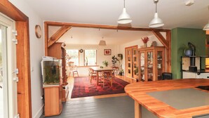 Eine Küche mit Holzbalken, einem Aquarium, einem Essbereich mit rotem Teppich und einer grünen Wand.