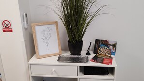 A desk with a framed botanical drawing, a potted plant, a keyboard, and a travel brochure. - Studio Apartment Enter - Studio Apartment With Terrace (Karlovac)