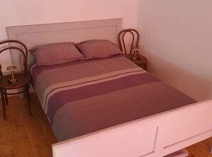 Un lit avec une tête de lit, deux tables de chevet et une couvre-lit à rayures.