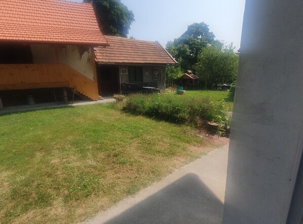 Une maison avec un toit recouvert de tuiles rouges, une pelouse devant et un petit jardin.