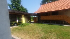 Un bâtiment doté d’un toit recouvert de tuiles rouges et d’une zone abritée avec un mur jaune.