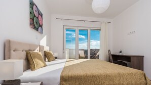A modern hotel room with a bed, desk, and balcony. - Comfort Four Bedroom Villa with Sea View and Private Pool ( Villa 7) (Debeljak)