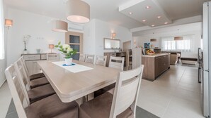 A modern kitchen with a central island, built-in appliances, and a dining area with a long table and chairs. - Comfort Four Bedroom Villa with Sea View and Private Pool ( Villa 7) (Debeljak)