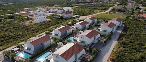 A residential area with modern houses, a swimming pool, and a road.