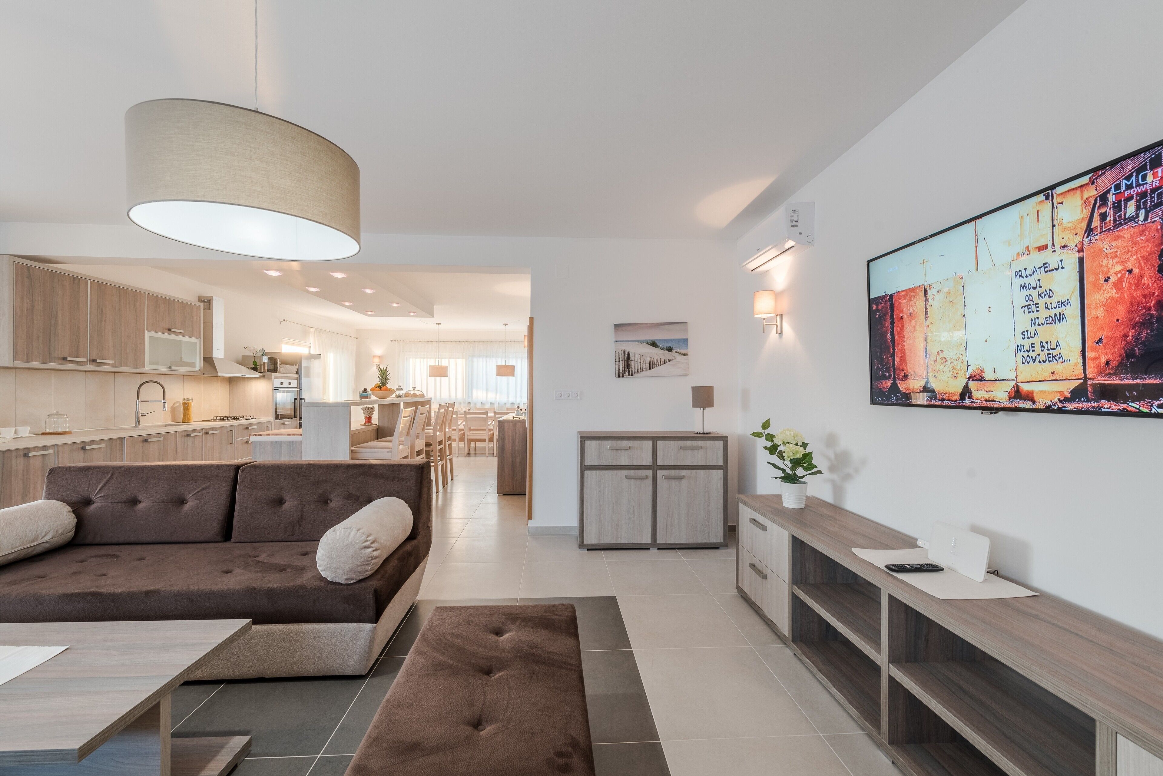 Un salon moderne avec un canapé marron, une table basse en bois et un téléviseur fixé au mur.