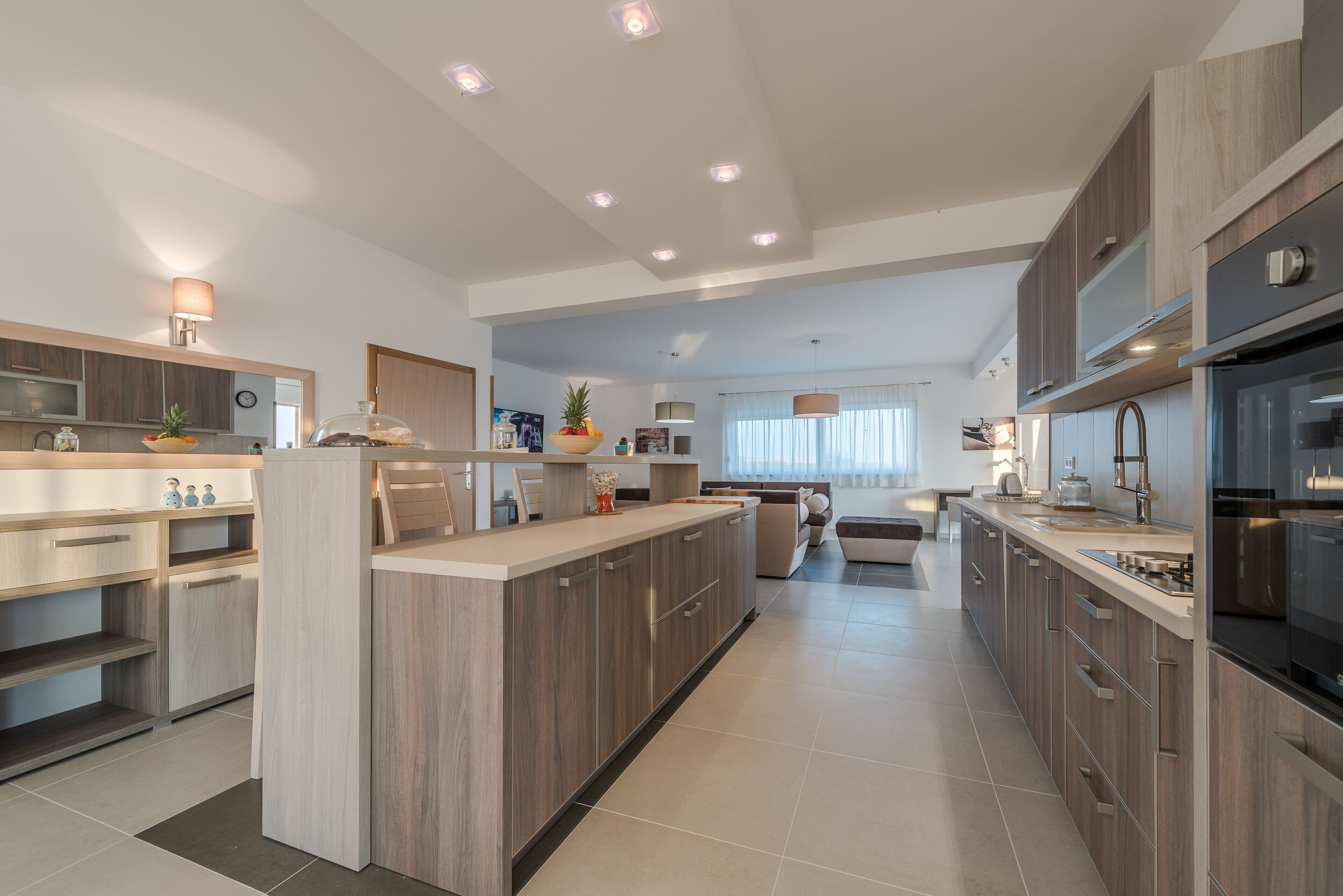 A modern kitchen with wooden cabinets, a central island, and built-in appliances.