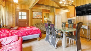 Ein gemütliches Zimmer mit einem Bett, einem Esstisch mit Stühlen, einem Fernseher und einer Küchenzeile.