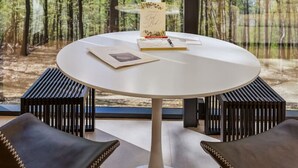 Una mesa redonda con mantel blanco, una lámpara colgante y un atril para menús con diseño floral.