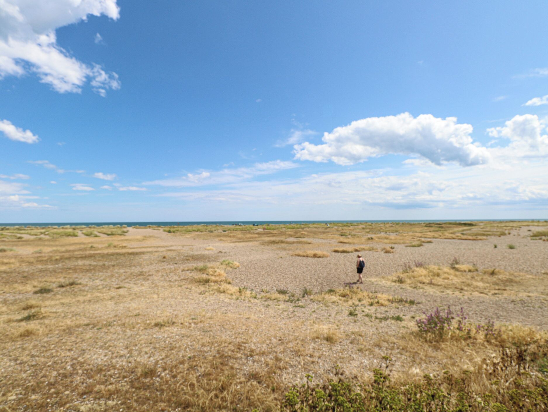 Un paisaje amplio y abierto, con una persona caminando a lo lejos.