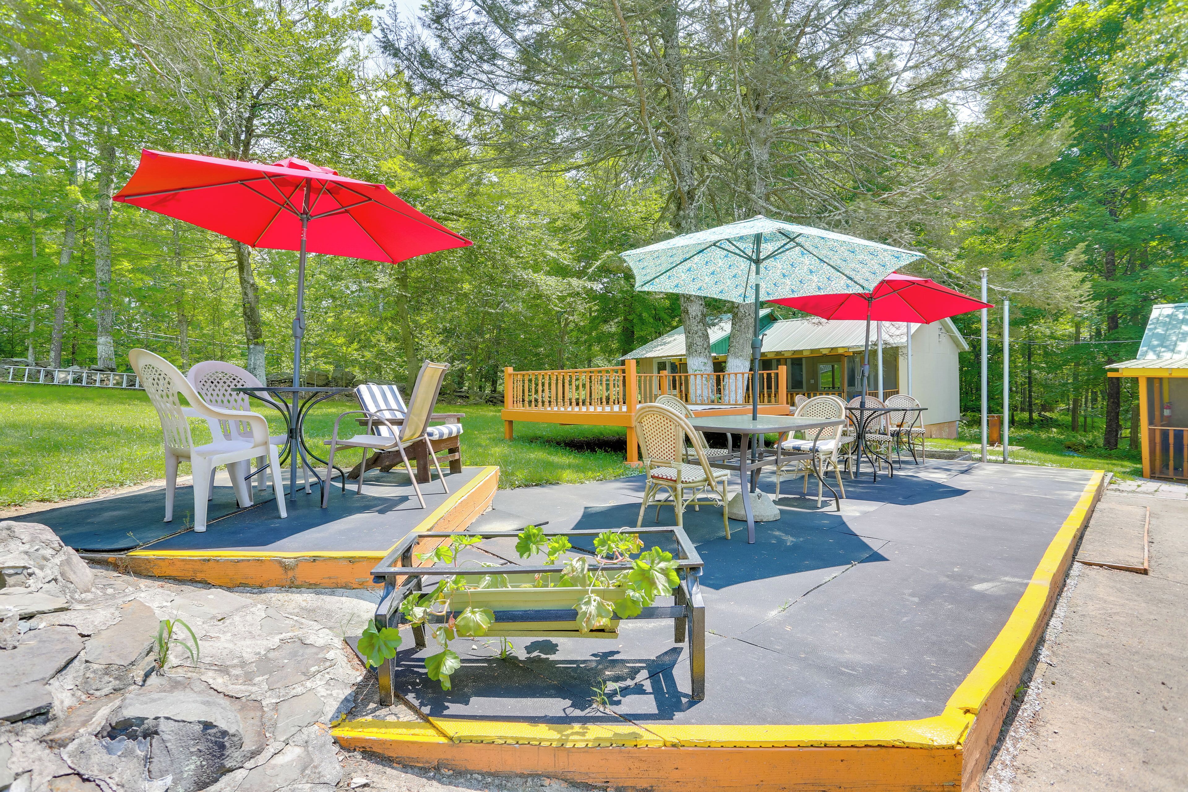 Une terrasse extérieure avec des tables et des chaises, entourée d’une plateforme en bois et d’un petit bâtiment.