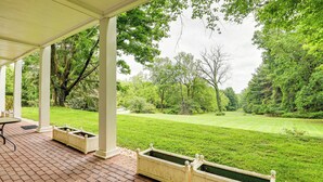 A covered patio with brick flooring, white columns, and planters. - 16 Mi to Baltimore: Spacious Home in Owings Mills! (Owings Mills)