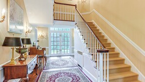 A grand staircase with wooden steps and white railings, leading to a door with glass panels. - 16 Mi to Baltimore: Spacious Home in Owings Mills! (Owings Mills)