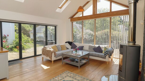 A spacious living room with a large sofa, a coffee table, and a fireplace. - Guildford Farmhouse (Ryde)