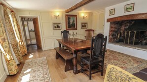 A dining area with a wooden table and chairs, a bench, a patterned rug, and a fireplace. - Guildford Farmhouse (Ryde)