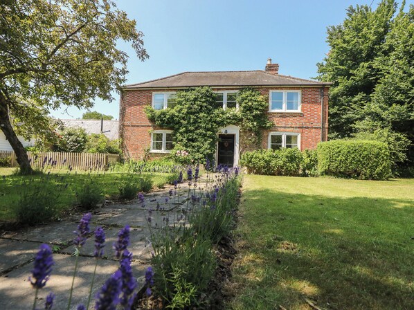A two-story brick house with a front garden and a pathway leading to the entrance.