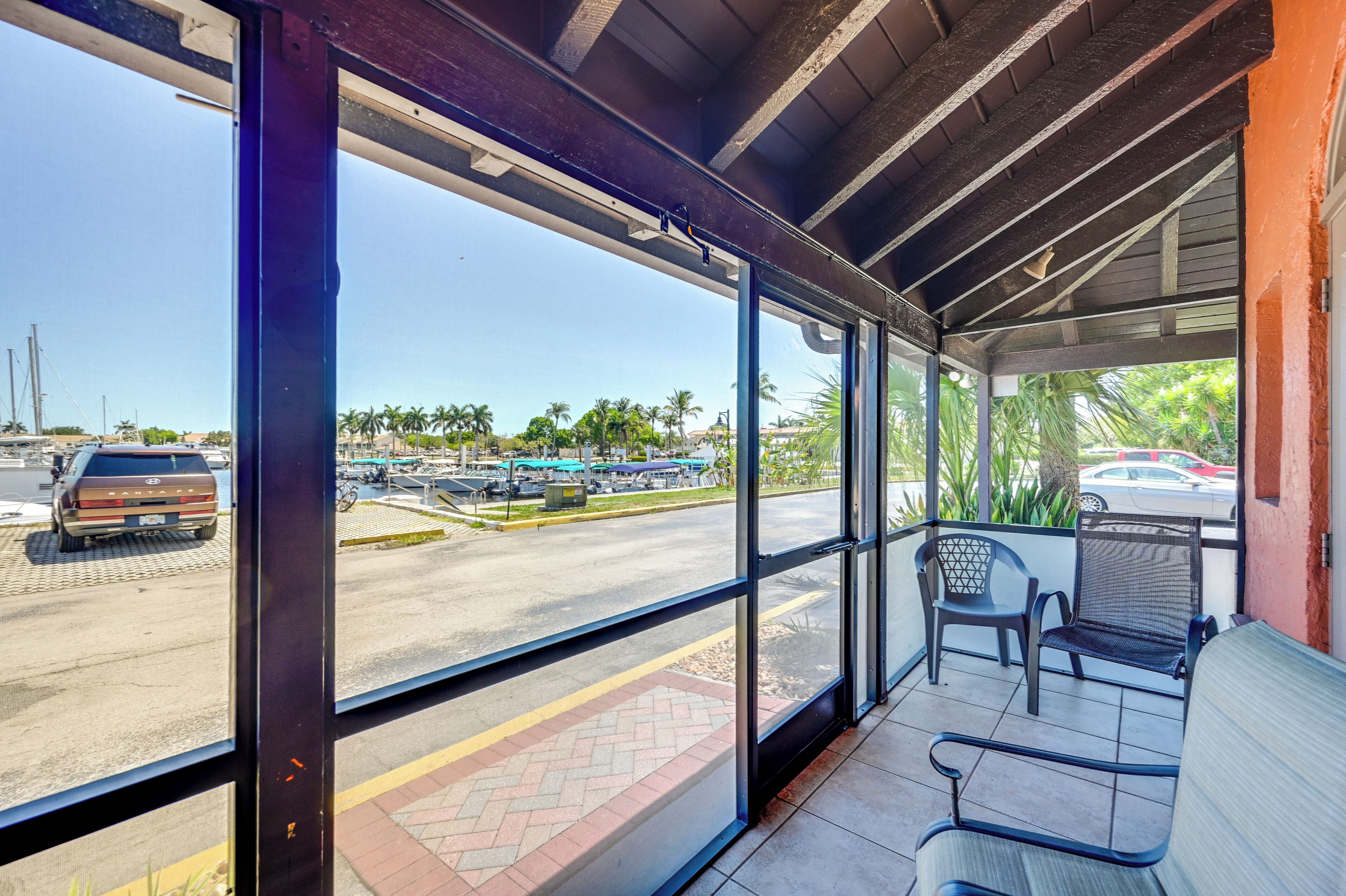 A covered outdoor seating area with a view of a parking lot and palm trees.