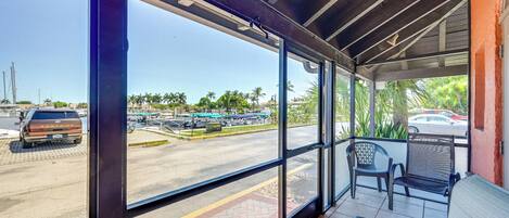 A covered outdoor seating area with a view of a parking lot and palm trees.