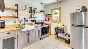A modern kitchen with stainless steel appliances, wooden shelves, and a window providing natural light. - 5 Mi to Joshua Tree National Park: Desert Oasis! (Twentynine Palms)