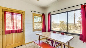 A room with a wooden table, bench, and two windows with red curtains. - 5 Mi to Joshua Tree National Park: Desert Oasis! (Twentynine Palms)