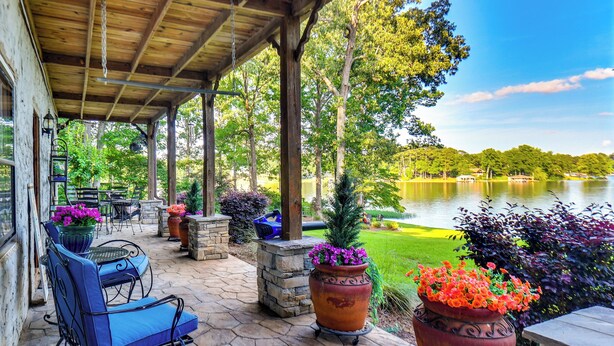 A covered patio with stone flooring, outdoor furniture, and large flower pots. - Waterfront Cabin on Lake Sinclair w/ Private Dock! (Eatonton)