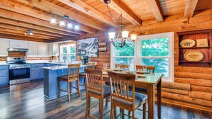 A wooden cabin interior with a kitchen, dining area, and large windows. - Waterfront Cabin on Lake Sinclair w/ Private Dock! (Eatonton)