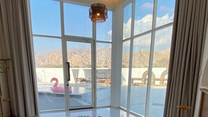 Une chambre spacieuse avec un grand lit, une vue sur les montagnes et une piscine agrémentée d’un flamant rose.