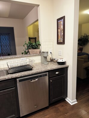 A kitchen with a built-in dishwasher, a coffee maker, and a potted plant on the counter. - Cozy convenient family-sized townhouse. 5-15 minutes to Shops, RTP, UNC, Duke (Durham)