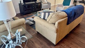A living room with a sofa, armchairs, a glass coffee table, a TV, and a cabinet. - Cozy convenient family-sized townhouse. 5-15 minutes to Shops, RTP, UNC, Duke (Durham)