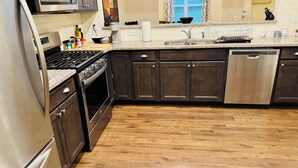A modern kitchen with dark cabinets, stainless steel appliances, and a wooden floor. - Cozy convenient family-sized townhouse. 5-15 minutes to Shops, RTP, UNC, Duke (Durham)