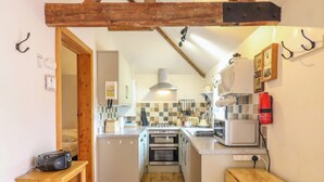 A compact kitchen with wooden beams, a refrigerator, a microwave, and a toaster.