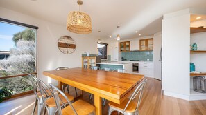 A modern kitchen with white cabinets, a wooden dining table, and a large window overlooking a garden. - Pet Friendly - Hopewell House with Spa and Golf Course Views (St Andrews Beach)